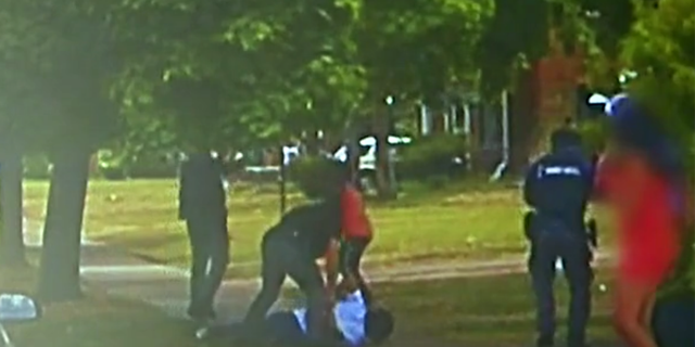 Police footage show officers arresting Darnell Sylvester moments before his friend, Hakeem Littleton (in orange shirt) opens fire on officers. 