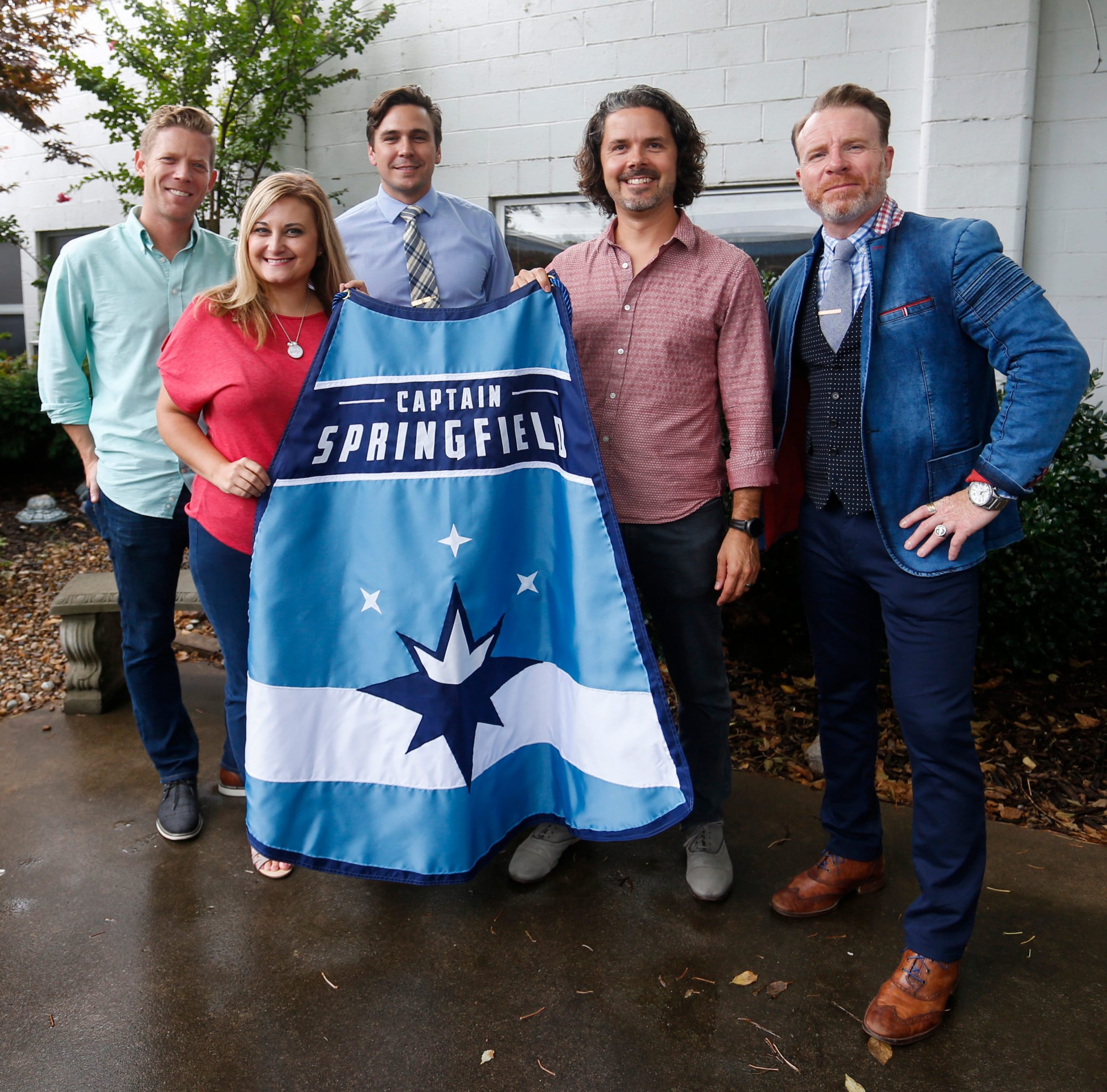 Janelle Reed, the outreach and special events manager for Victory Mission, is presented a Captain Springfield cape by (from left) Jeff Houghton, Joel Thomas, John McQueary and Sean Brownfield.
