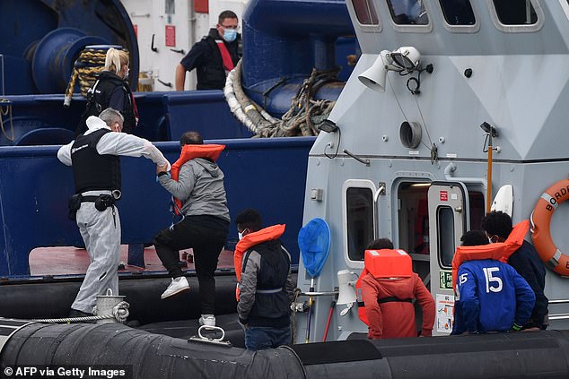 Officials were seen helping the migrants - all wearing orange life jackets - off the boat and onto dry land
