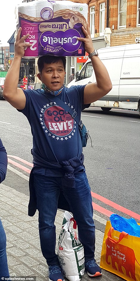 A customer balances toilet roll on his head after hitting the shops in Camden Town